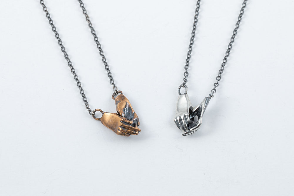 
            
                Load image into Gallery viewer, Holding hand necklaces in silver and bronze by Alice Scott.
            
        